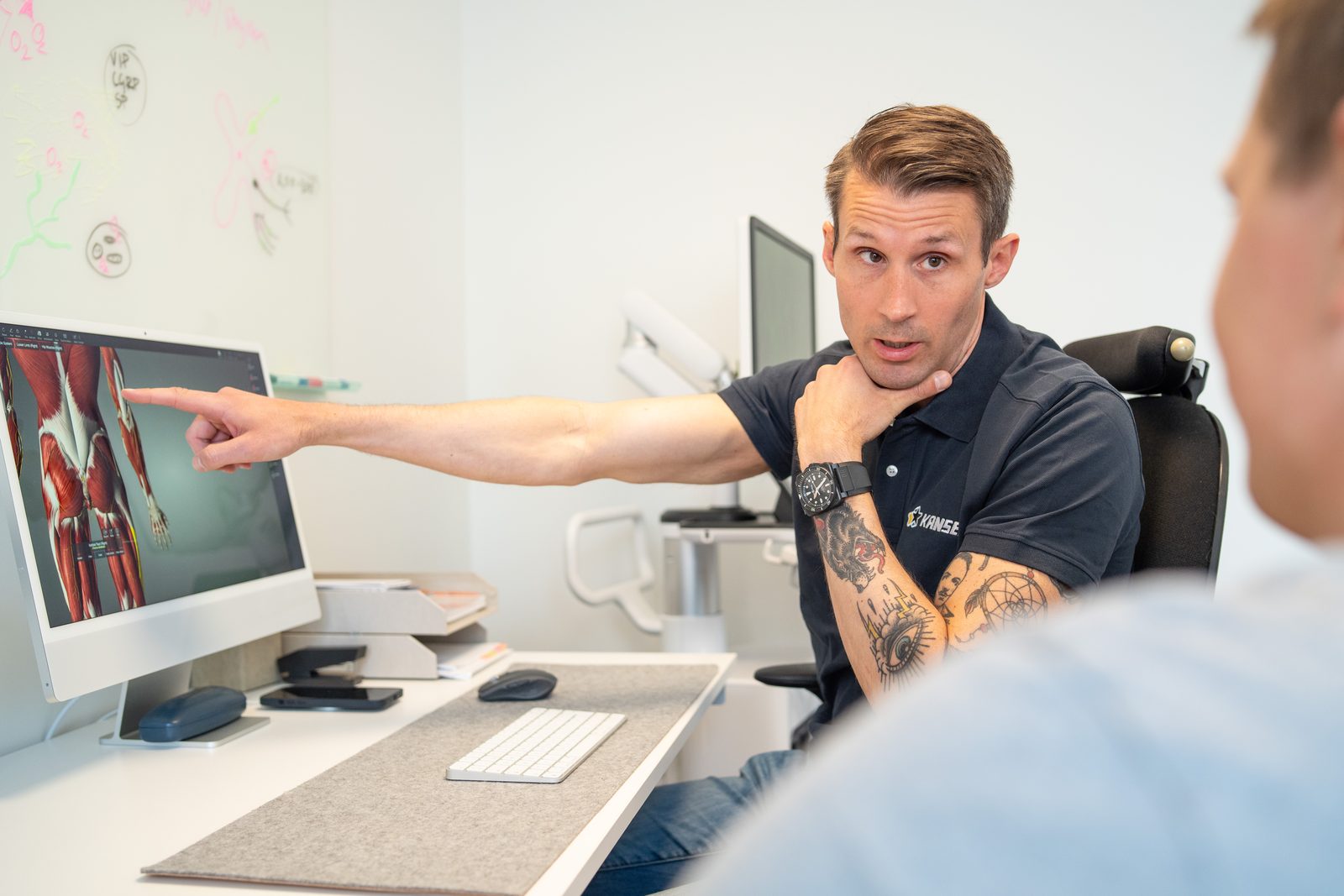 Carl-Robert pekar på anatomibilder på skärmen och förklarar fynden för patienten